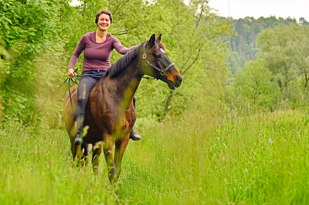 Sarah Bähler beim Ausritt mit Pferd im Wald